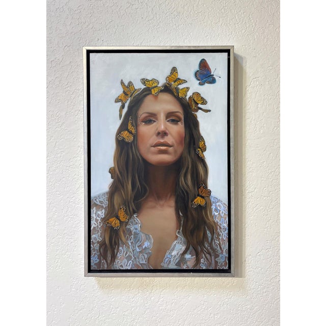 This artwork depicts a serene figure adorned with a crown of butterflies, creating a striking contrast against a soft,...