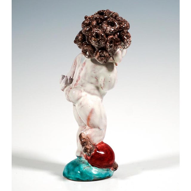 Figure of a standing, curly-haired cupid, a stylized interpretation of ancient models, at his feet a large heart pierced...