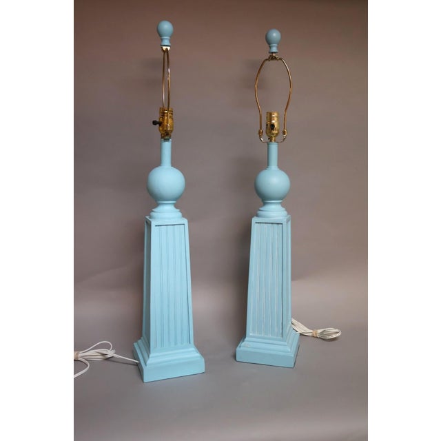 A striking pair of late 20th century neoclassical style table lamps featuring tall fluted obelisk forms in a soft matte...