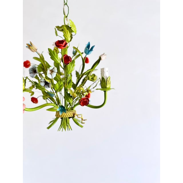 Vintage painted tole chandelier with three light arms and hand-formed floral and foliate decoration. The fixture features...