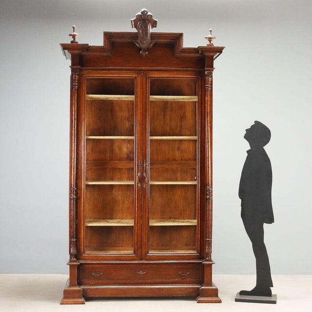 Late 19th-century walnut display cabinet from Italy, featuring an elegant structure with a pair of glass doors and a...