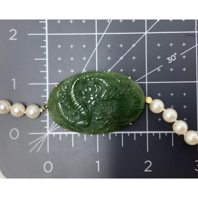 18K Yellow gold and carved jade pendant on cultured pearl strand of (74) white pearls, measuring 23.5" in length. GIA...
