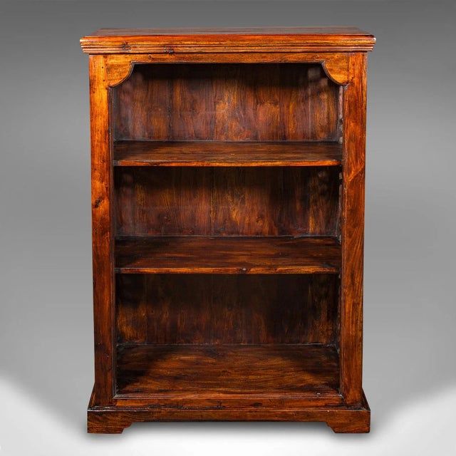 This is a vintage open bookcase. An Asian, stained Hevea and cast iron shelving unit in Regency and Colonial revival...