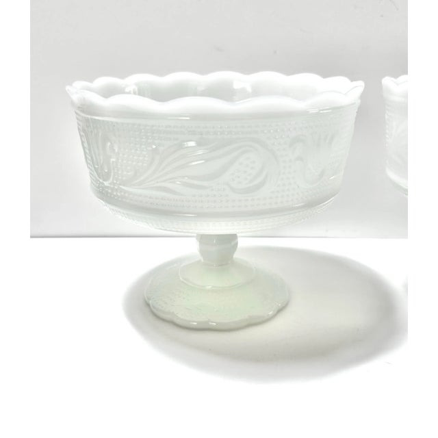 A charming pair of vintage American milk glass pedestal compotes attributed to E.O. Brody. Featuring scalloped rims and...