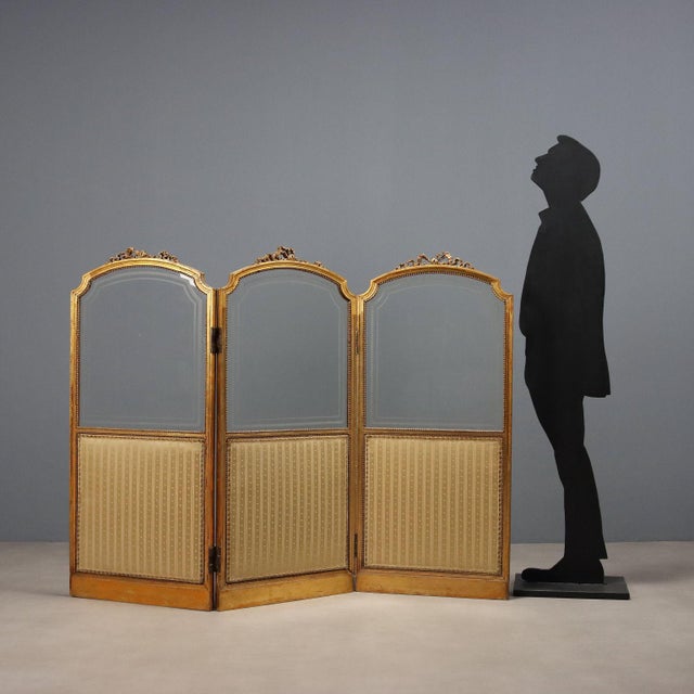 Gilded wood screen. Three panels with a glass upper section with an etched frame and a fabric-covered lower section....