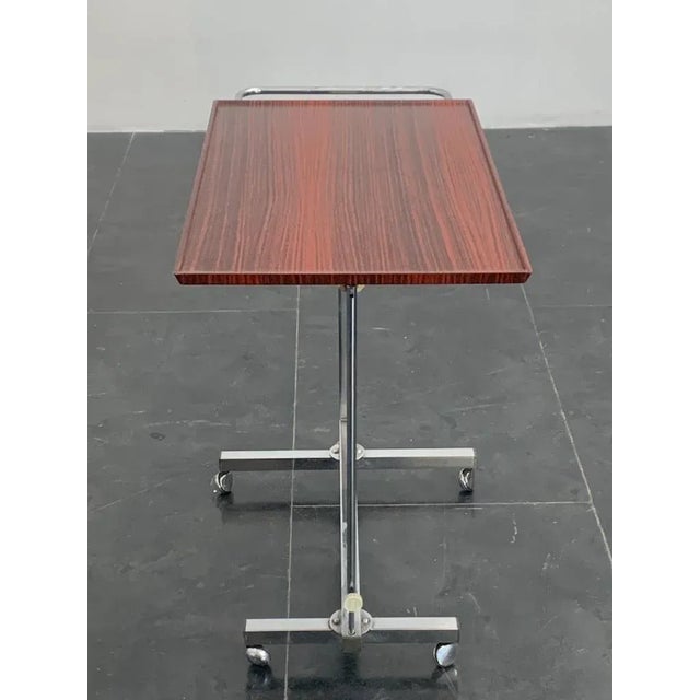 The table is continuously adjustable from height 66 to 97 cm the 40cm x 65 plane is lockable. Chromed metal and rosewood...