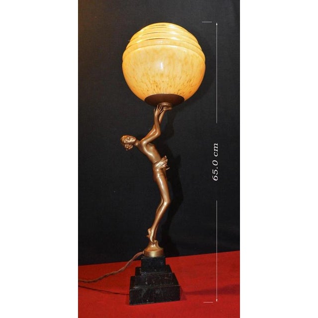 A striking french art deco table lamp dating to the 1930s, combining sculptural bronze, veined marble and opaline glass in...