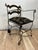 A striking vintage wrought iron armchair featuring a sculptural curule-style base, gracefully scrolled arms and feet, and...