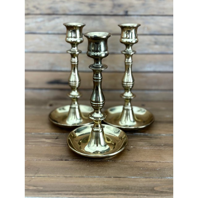 A handsome set of three vintage solid brass chamberstick candle holders, each stamped England on the base and paired with...