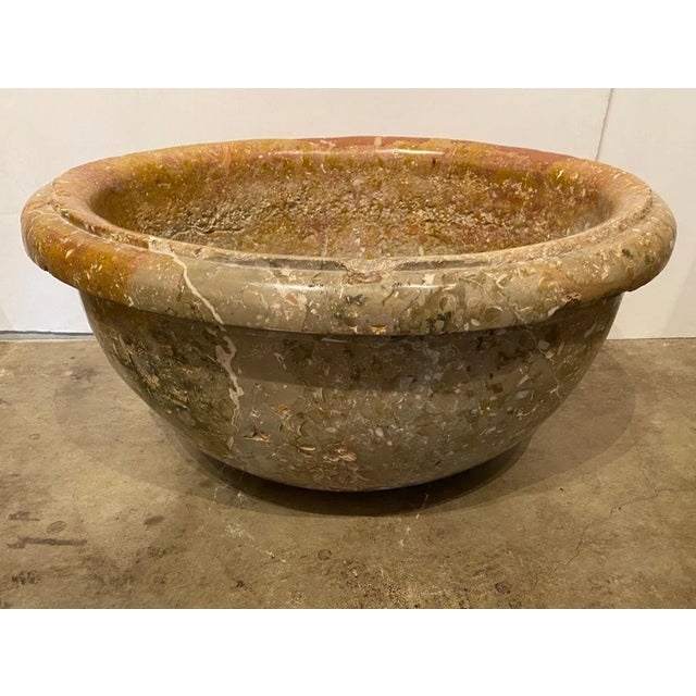 A hand carved, oval shaped rimmed basin with drainage hole.