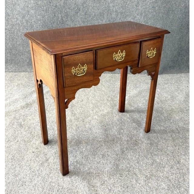 This solid mahogany console table features clean lines, a shaped apron, and classic brass batwing pulls for a timeless...