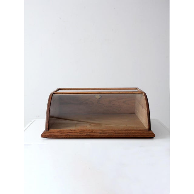 This vintage European display case features a curved glass front and a warm wood frame, with balanced, architectural...