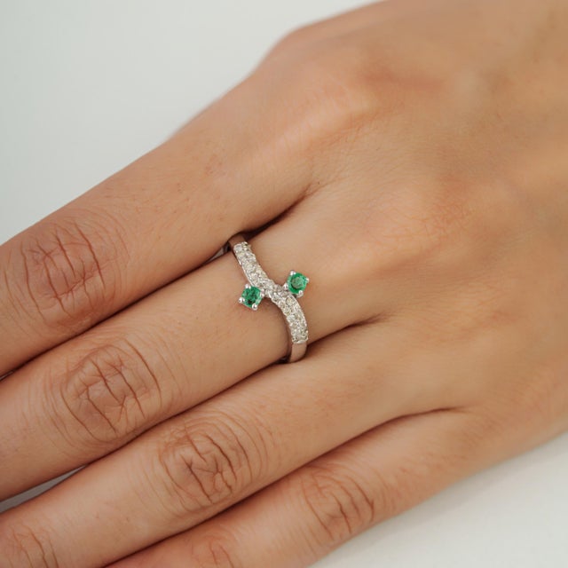 This elegant ring is crafted in 925 sterling silver, featuring a 0.22-carat round natural emerald complemented by 0.28...