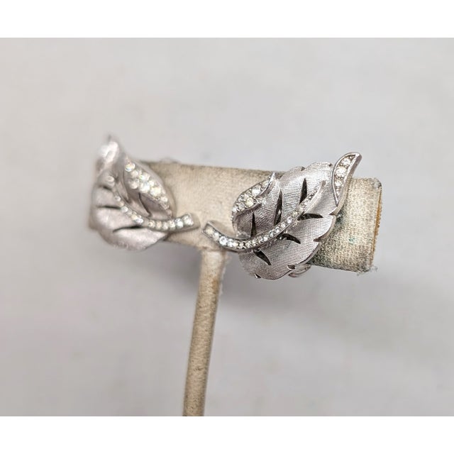 1960 rhodium plated Florentine finish leaf with curled edge and tip set with round clear rhinestones with cut outs in the...