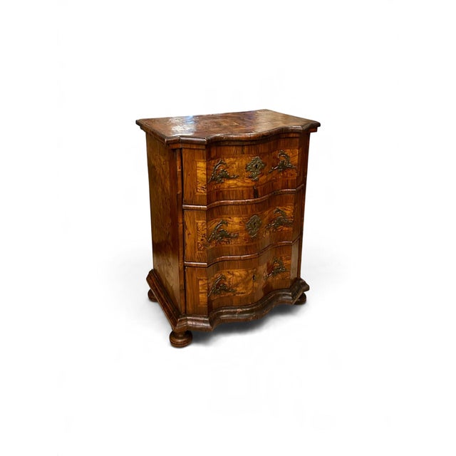 An elegant 18th-century German walnut commode, the serpentine façade fitted with three drawers, each adorned with richly...