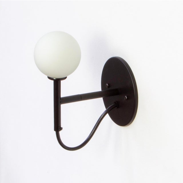 An exposed cord loops playfully across a minimal arm. The Loop Sconce brings glow and character in equal measure.