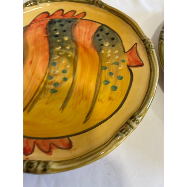 Vibrant pair of Italica Ars ceramic plates from Italy, each featuring a bold, hand-painted tropical fish motif on a warm...