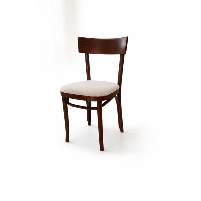 A sculptural set of six vintage dining chairs defined by rare serpentine lower rails and freshly reupholstered neutral...