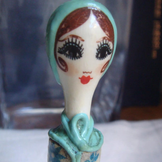Popular in 1960s for use with lipstick refills. Believed to be paper mache. Her "robe/dress" is a blue floral on off-white...
