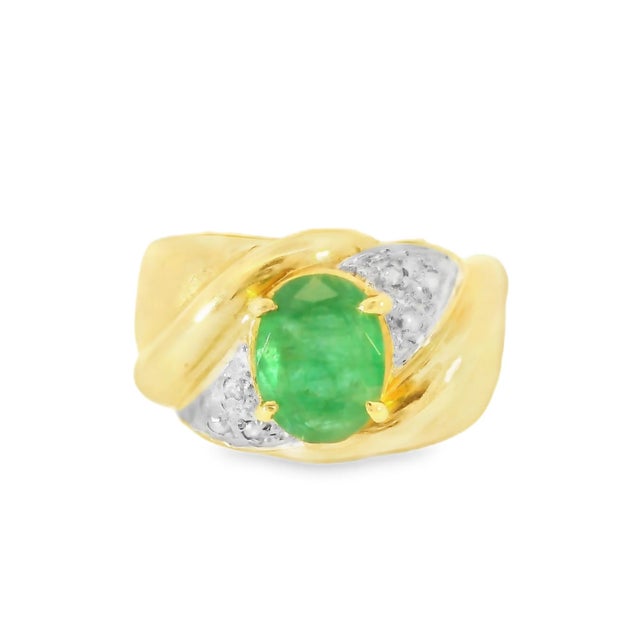 Estate 14K yellow gold ring featuring a natural oval emerald flanked by six round diamonds, a timeless and elegant design....