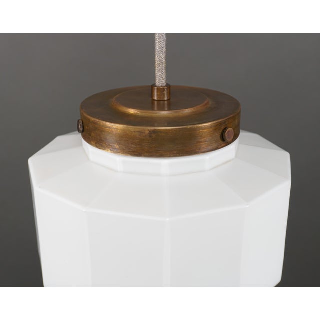 An original near-antique art deco pendant lamp of opaque white glass with a stepped design and faceted/panelled sides,...