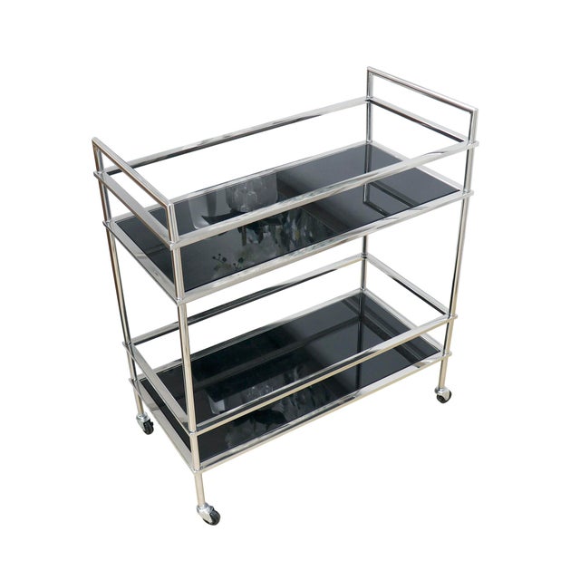This elegant Luxe bar cart boasts a lustrous stainless steel frame complemented by black mirrored glass shelves, offering...
