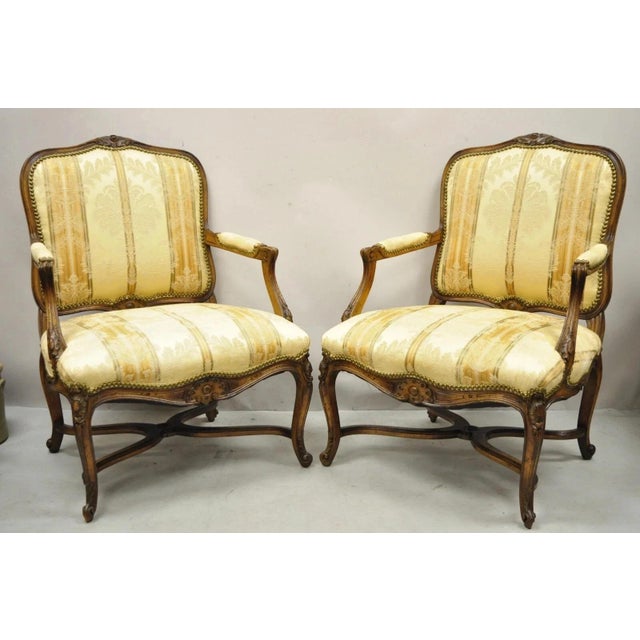 Vintage French Country Louis XV Style Carved Walnut Lounge Arm Chairs - a Pair. Item features cross stretcher base, beige...