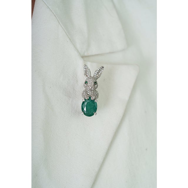 This bunny brooch features a vibrant 3.08 carat emerald Crafted in 14K white gold, measuring approximately 9 x 12.11 mm,...