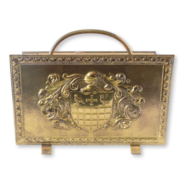 This midcentury French brass magazine rack features a striking family coat of arms pressed into the brass, along with...