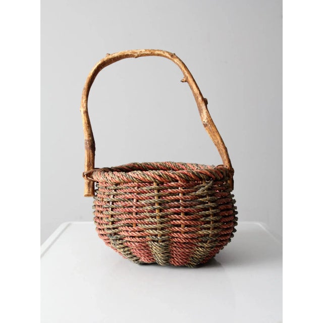 This is a vintage handle basket. The red and green country basket features a tall rustic wooden handle.