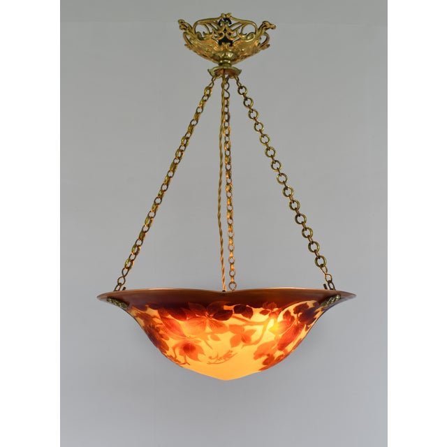 établissement Émile Gallé A French art deco hanging fixture in gild bronze with a Gallé bowl in acid-engraved cameo glass....