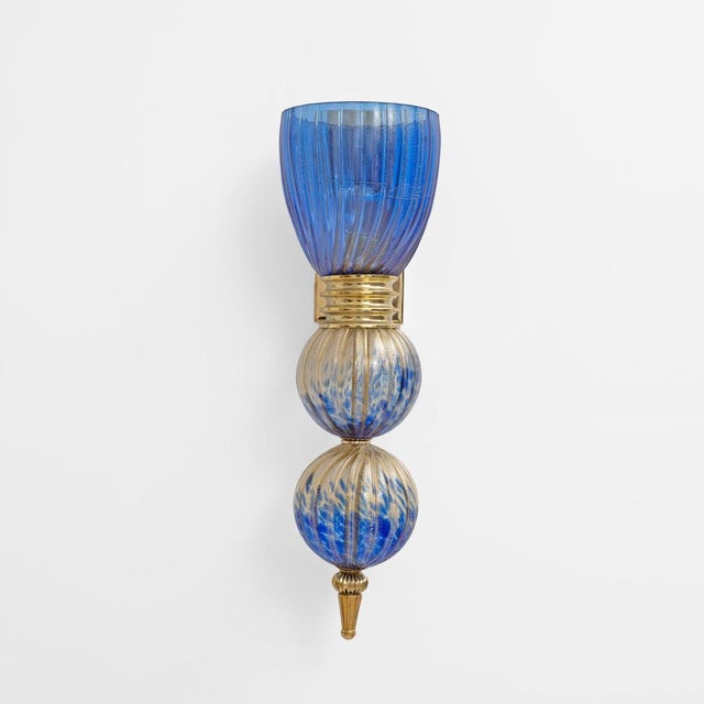 An elegant pair of wall sconces, handcrafted from murano glass and brass, featuring a refined ribbed texture enriched with...