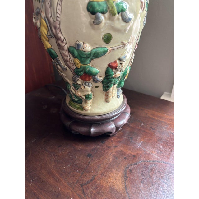 Table lamp made from a porcelain vase with raised polychrome relief figures of warriors among trees in green, yellow, and...
