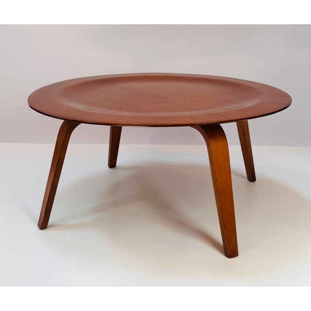 This iconic Eames table features a gently dished circular top in richly toned molded plywood. It is raised on four splayed...
