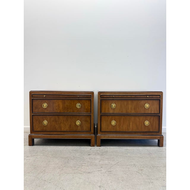 A refined pair of Drexel Heritage nightstands featuring beautifully bookmatched burl wood veneer drawer fronts framed in...