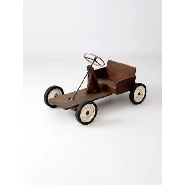 A vintage toy riding car. The large wood car "cart" has a metal frame with wood seating. The front wheels move with the...