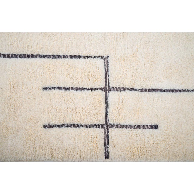 Elegant hand-knotted wool rug in Antique White, featuring an abstract grid pattern in deep Caviar. The bold, intersecting...