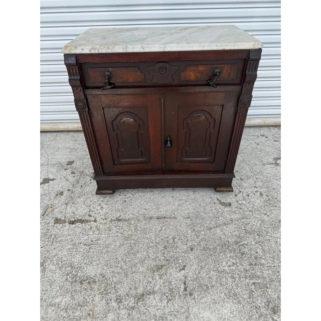 This is a late 19th Century Mahogany Victorian Cabinet. The cabinet has a marble top and a single drawer. It also has...
