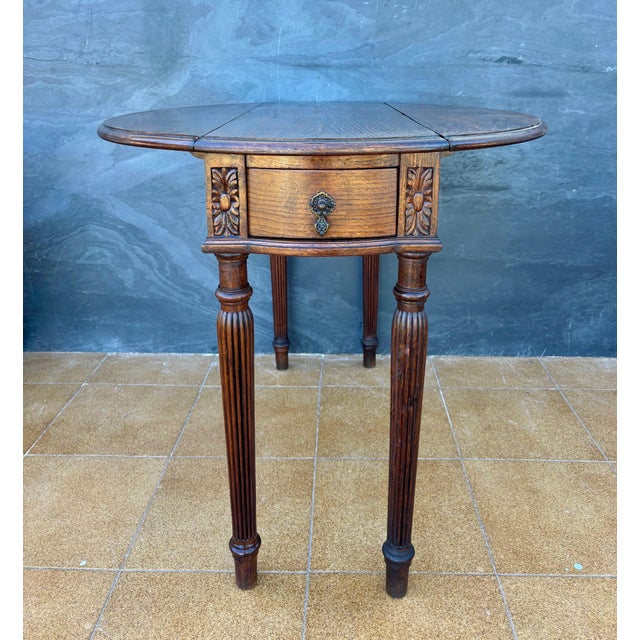 Spanish Neoclassical drop-leaf table crafted in oak, dating to the early 20th century. The table features a circular top...