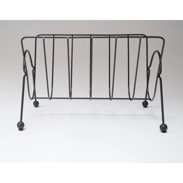 Black wire magazine rack supported by rubber orb feet (ca. 1950s, USA). Reminiscent of a similar design by Tony Paul, but...
