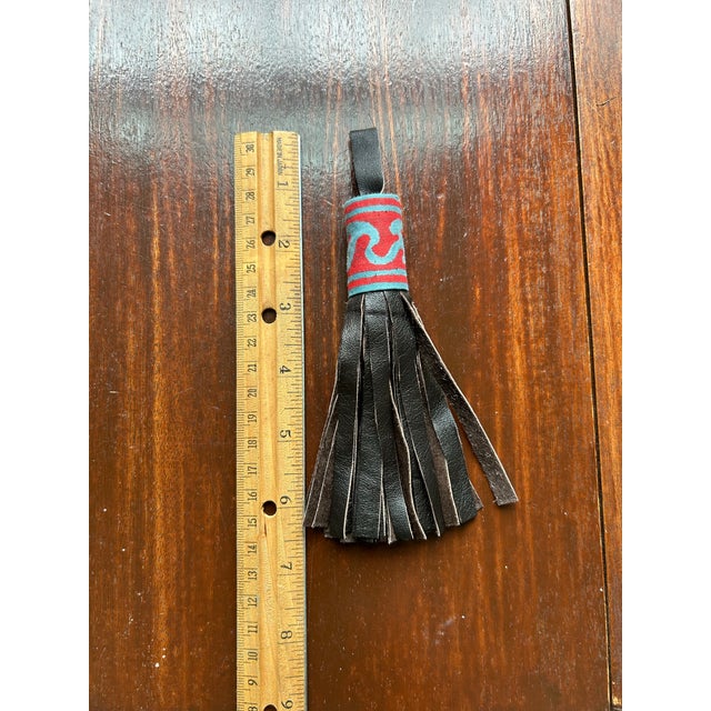 A tassel handmade from a Fortuny fabric border and leather.