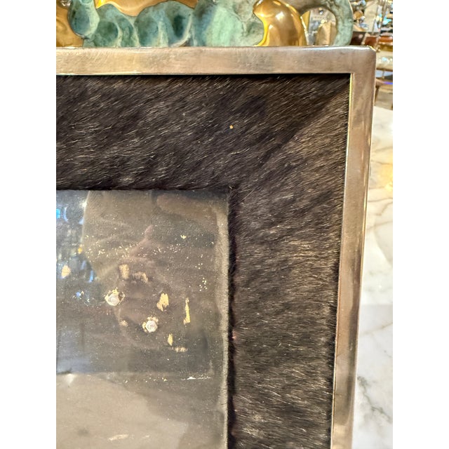 A distinctive Italian photo frame from the 1970s, combining sleek silvered metal with rich dark pony hair for a refined...
