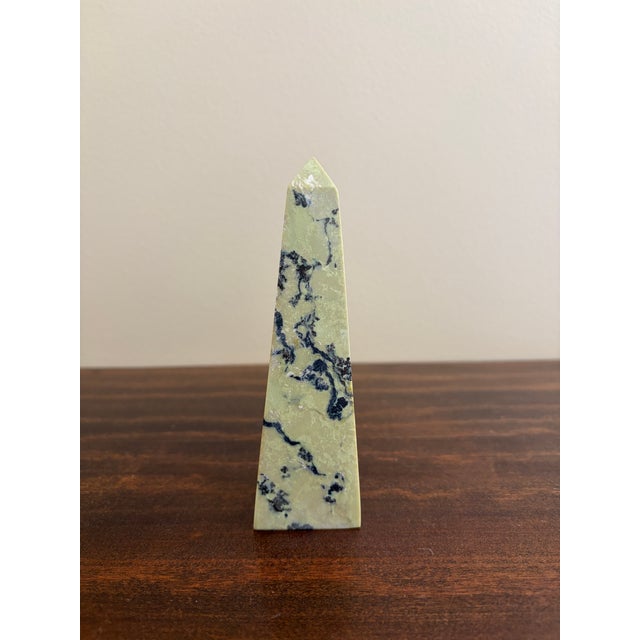 A beautifully proportioned marble obelisk in richly veined shades of yellow, cream, grey, and black. The sculptural...