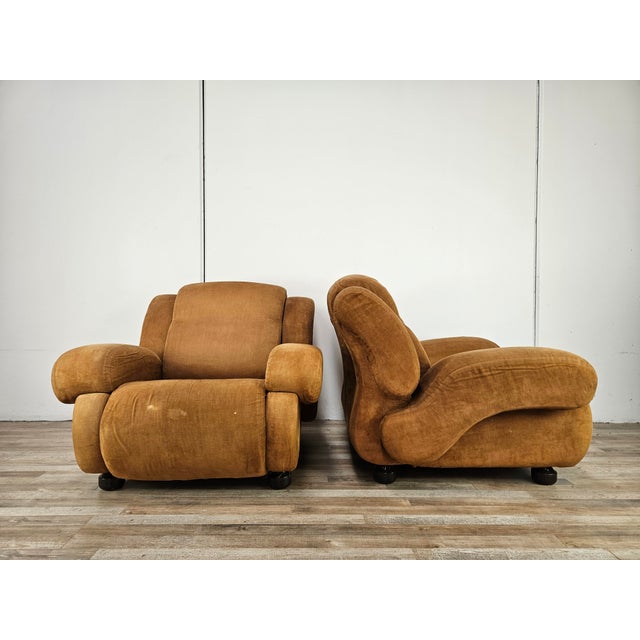 A pair of large 1970s Italian armchairs in light brown fabric, perfect for modern or vintage settings. They are in...