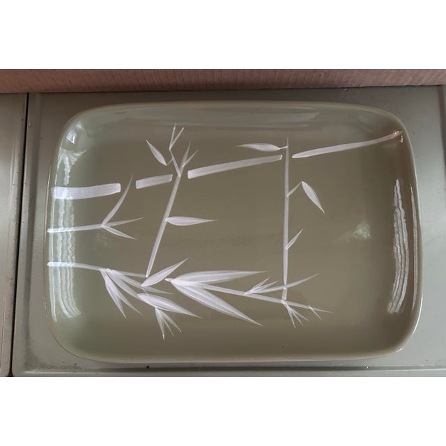 This elegant mid-century ceramic serving platter features a soft sage green glaze and a minimalist white bamboo design,...
