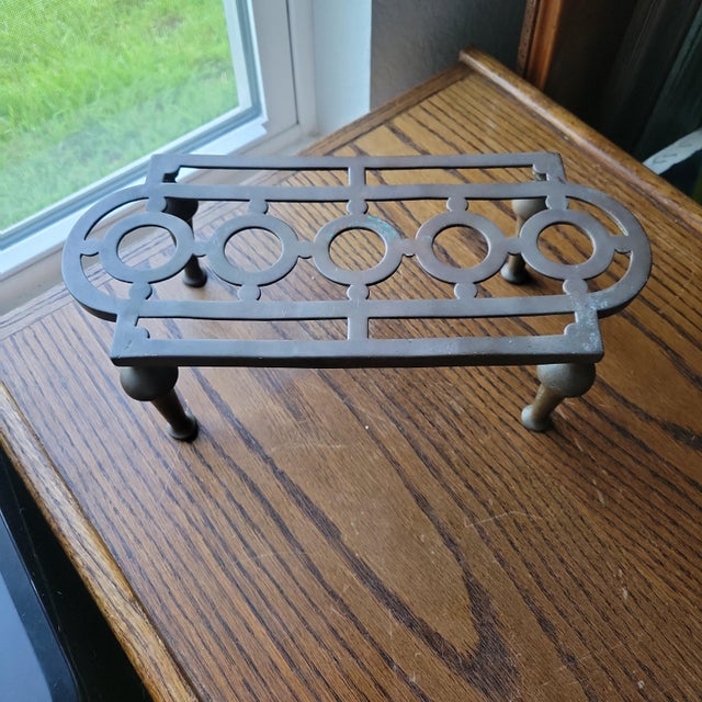 This antique solid brass kettle stand trivet, also known as a plant pot riser, is a handmade piece originating from...
