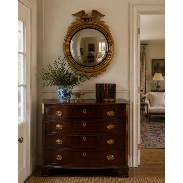 A handsome mid-20th-century American Federal-style convex mirror with a richly gilt frame, carved eagle crest, and layered...