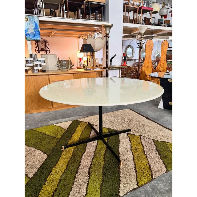 1970s-style dining table with a round light marble top, featuring an elegant, luminous surface that enhances any space....