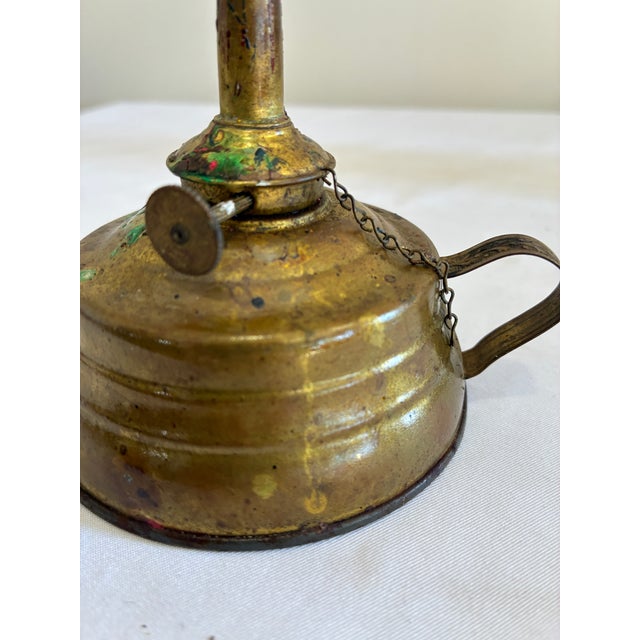 A late 19th to early 20th century brass finger oil lamp featuring a traditional loop handle and squat reservoir form. This...