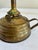 A late 19th to early 20th century brass finger oil lamp featuring a traditional loop handle and squat reservoir form. This...